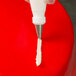 A hand using an Ateco leaf piping tip to pipe white frosting on a cake.