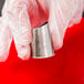 A hand holding a metal Ateco U-Shape Ruffle Piping Tip over a metal container.