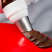 A person using an Ateco U-shape ruffle piping tip to decorate a brown pastry.