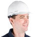 A man wearing a Cordova white cap style hard hat with a 6-point ratchet suspension smiles at the camera.