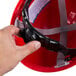 A person holding a red Cordova Duo safety hard hat with a strap.