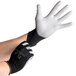 A pair of hands wearing black and white Cordova warehouse gloves.