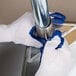 A person wearing blue Cordova work gloves holding a metal pipe.