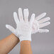 A pair of hands wearing white Cordova inspection gloves.