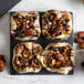 A plate of desserts with nuts and chocolate drizzled on a black slate Acopa plate.