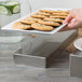 A Tablecraft rectangular stainless steel bowl filled with cucumber slices on a table.