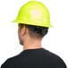 A man wearing a green hi-vis hard hat with a full brim.