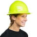 A woman wearing a green Cordova full-brim hard hat with a 4-point ratchet suspension smiling.