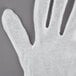 A white Cordova lisle glove with four fingers on a gray surface.