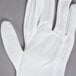 A pair of white Cordova inspector's gloves on a gray surface.