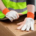 A person wearing Cordova cotton canvas work gloves holding a cardboard box.