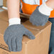 A person wearing Cordova loop-out gray jersey gloves and holding a box.