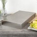 A Tablecraft stainless steel rectangular bowl on a wood table.