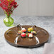 A Bon Chef mahogany lazy susan turntable on a wooden table with spoons on it.