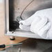 A hand in a white Cordova glove using a screwdriver to hold a screw.
