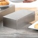 A silver rectangular stainless steel bowl filled with food on a table.