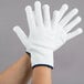 A pair of hands wearing white Cordova nylon work gloves with blue trim.