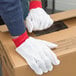 A person wearing Cordova red polyester and cotton double palm work gloves.