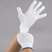 A hand wearing white Cordova work gloves with blue trim.