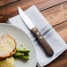 A Walco stainless steel steak knife on a plate of food