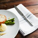 A plate of food with a Walco Lancer steak knife and fork on a napkin.