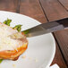 A Walco steak knife cutting a piece of meat on a plate.