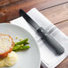 A plate of food with a Walco stainless steel steak knife on a napkin.