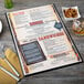 A black Menu Solutions menu board on a table with a fork and knife.