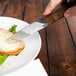 A person using a Walco steak knife to cut a piece of meat.