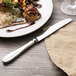 A Walco Lancer stainless steel dinner knife next to a plate of food