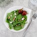 A Villeroy & Boch white porcelain plate with a spinach salad, bacon, feta, and cherry tomatoes with a fork and a glass of water.