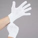 A pair of hands wearing white Cordova work gloves.