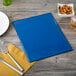 A blue Menu Solutions Hamilton menu board with a fork and knife next to a plate and napkin.