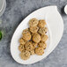 A Villeroy & Boch white premium porcelain oval platter with cookies and a glass of milk on it.