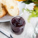 A jar of jam next to Acopa round glass sauce cups filled with bread and a knife.