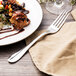 A plate of food with a Walco Lancer dinner fork and a napkin.