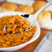 A close up of a Walco 18/10 stainless steel serving spoon filled with rice.