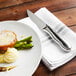 A plate of food with a Walco steak knife, meat, and asparagus.
