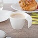 A white Villeroy & Boch porcelain cup with a handle filled with coffee on a table.