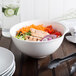 A Villeroy & Boch white porcelain salad bowl filled with salad on a table.