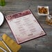 A Menu Solutions Hamilton menu board on a table with a wine glass and a fork.