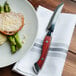 A plate of food with a Walco Denver Chop steak knife with a wooden handle.