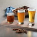 A wooden board with Acopa beer tasting glasses of beer and pretzels.