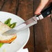 A person cutting a piece of meat with a Walco Boston Chop steak knife.