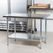An Advance Tabco stainless steel work table with a galvanized undershelf.