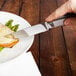 A person cutting a piece of meat on a plate with a Walco Ultimate customizable steak knife.