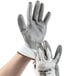 A pair of medium Cordova Caliber white gloves with gray polyurethane palms being held