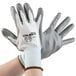 A pair of hands wearing white Cordova Caliber gloves with gray palm coating.