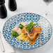 A plate of food on a Arcoroc Candour Azure porcelain dinner plate on a table.