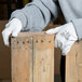 A person wearing Cordova Mirage white polyurethane palm coated gloves holding a piece of wood.